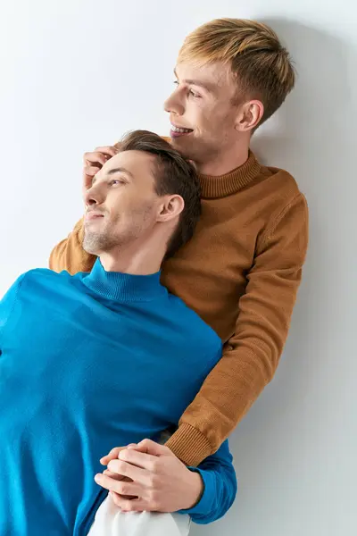 Two men, one in a blue sweater, sharing a warm hug on a gray backdrop. — Stock Photo