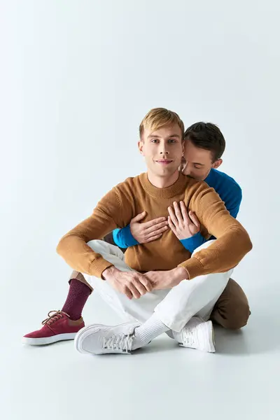 Two men sit closely, embracing each other with arms around, conveying love and connection. — Stock Photo