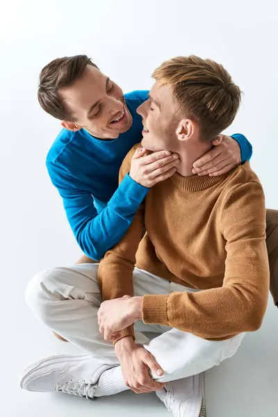 Two men sit closely together on the ground, exuding warmth and connection. — Stock Photo