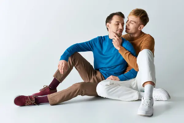 Zwei Männer in lässiger Kleidung sitzen mit ineinander verschlungenen Füßen auf dem Boden. — Stockfoto