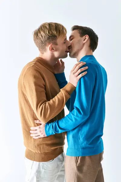 Dos hombres con atuendo casual se besan apasionadamente. - foto de stock