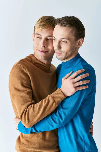 Hombres jóvenes con atuendo casual abrazándose frente a un fondo blanco. - foto de stock