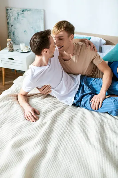 Un amorevole coppia gay in abbigliamento casual posa su un letto insieme. — Foto stock