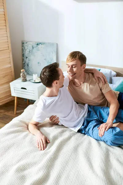 Two men sit on a bed, sharing a tender moment. — Stock Photo