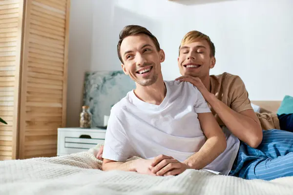 Two men in casual attire enjoying quality time together while sitting on top of a bed. — Stock Photo