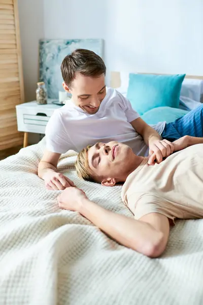 A loving gay couple in casual attire, laying together on a bed. — Stock Photo