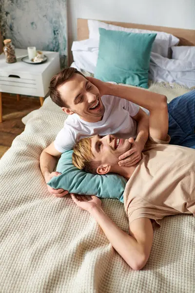 A loving gay couple relaxing on a bed in casual attire. — Stock Photo