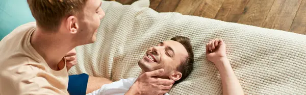 Un homme se prélasse sur un canapé à côté de son petit ami, créant une scène tendre et chaleureuse. — Photo de stock