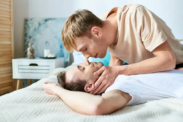 Two men peacefully embrace on a bed in casual attires. — Stock Photo