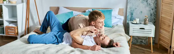 Deux hommes en tenue décontractée couchés ensemble sur un lit. — Photo de stock