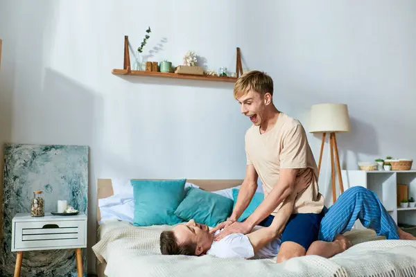 Man in casual attire sits on bed beside other man, spending quality time together. — Stock Photo