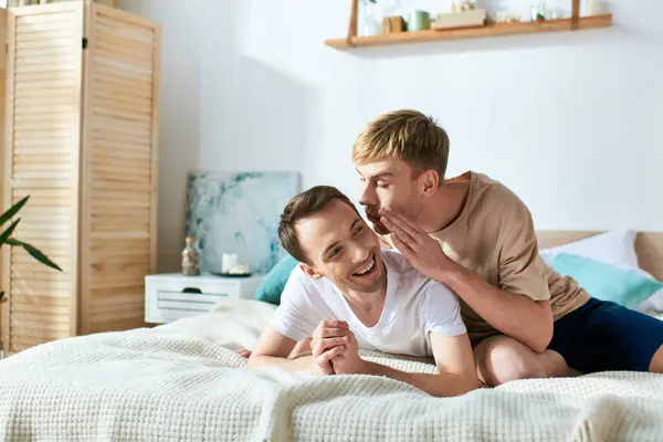 Two men in casual attire lay together on a bed. — Stock Photo