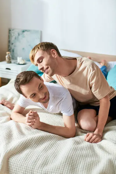 Two men in casual attire laying on a bed. — Stock Photo