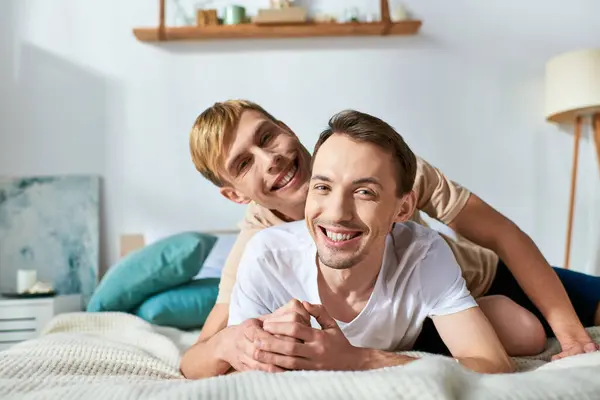 Two men in casual attire lay together on a bed. — Stock Photo