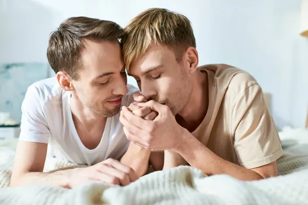 Two men in casual attire lying on a bed in a loving embrace. — Stock Photo