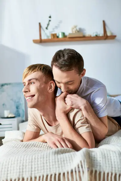 Two men in casual attire lie together on a bed, sharing a tender moment. — Stock Photo