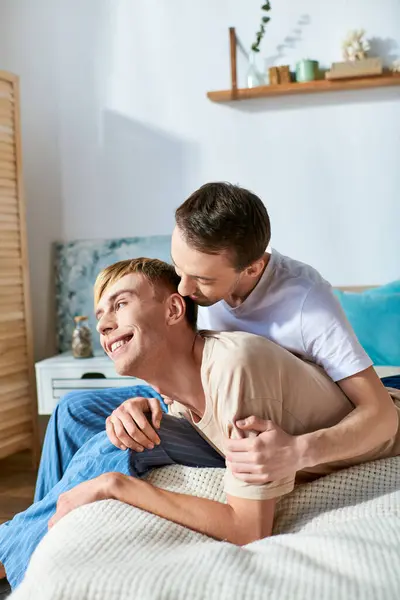 Un uomo in abbigliamento casual giace accanto a un altro uomo su un letto. — Foto stock