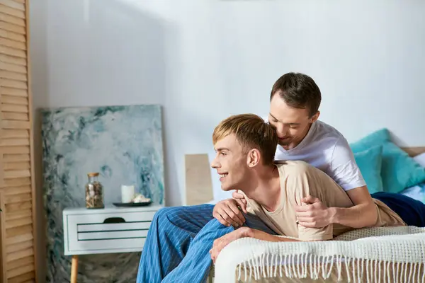 Un homme assis sur un lit à côté d'un autre homme en tenue décontractée, partageant un moment d'amour. — Photo de stock