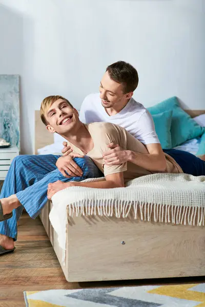 Un amorevole coppia gay in abbigliamento casual seduti insieme su un comodo letto, godendo ogni altri compagnia. — Foto stock