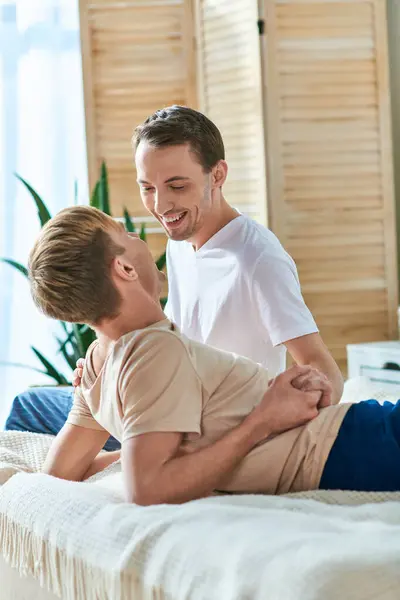 A man and his boyfriend share a tender moment while sitting on a bed. — Stock Photo