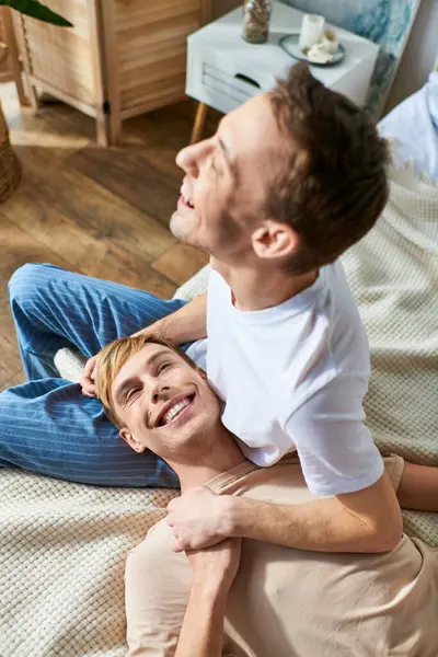 Ein Mann sitzt auf einem Bett, Arm um einen anderen Mann in intimen Moment. — Stockfoto