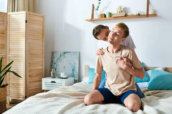Deux hommes partagent un moment confortable assis sur un lit. — Photo de stock
