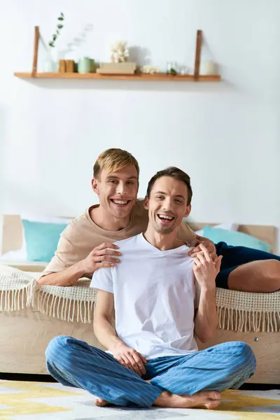 Two young men in casual attire sit on a bed, beaming with joy. — Stock Photo