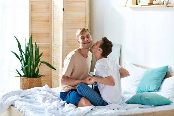 Two men in casual attire sitting and relaxing on a bed. — Stock Photo