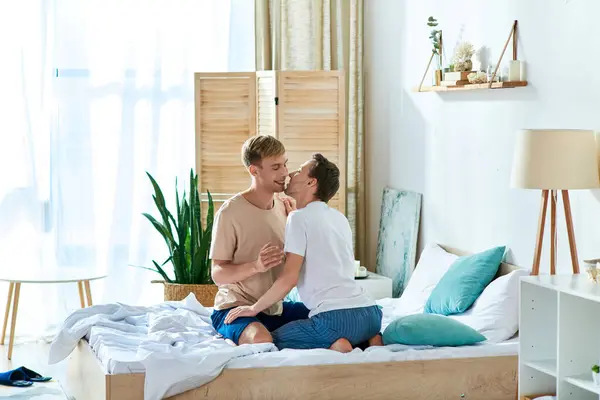 Casual gay coppia seduta comodamente su un letto. — Foto stock
