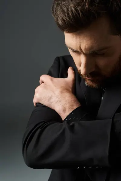 A man in a black suit standing with his hands clasped together. — Stock Photo