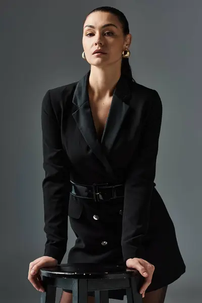 A sophisticated woman in elegant attire sitting gracefully atop a stool. — Stock Photo