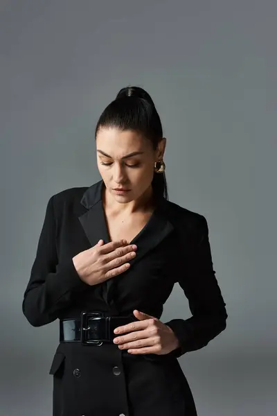 Una donna sofisticata in un abito nero, stringendo le mani insieme. — Foto stock