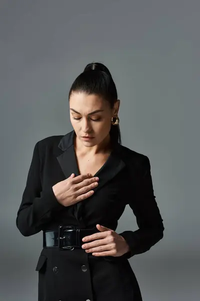 Una mujer sofisticada con un traje negro, apretando las manos. - foto de stock