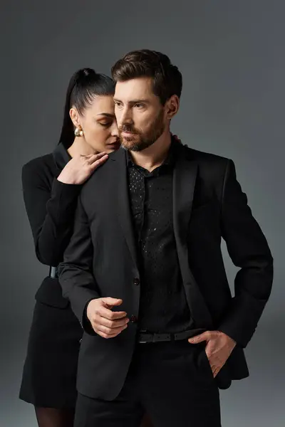 Un hombre y una mujer con un atuendo elegante se paran uno al lado del otro en una pose amorosa. - foto de stock