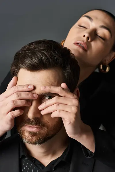Woman in elegant attire covering eyes of her boyfriend with hands. — Stock Photo