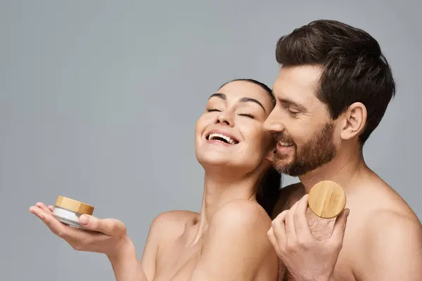 Atractiva pareja posando con tarro de crema, aplicando cuidado de la piel. - foto de stock