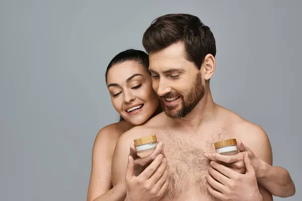 A man and woman holding a jar of cream, applying skincare. — Stock Photo