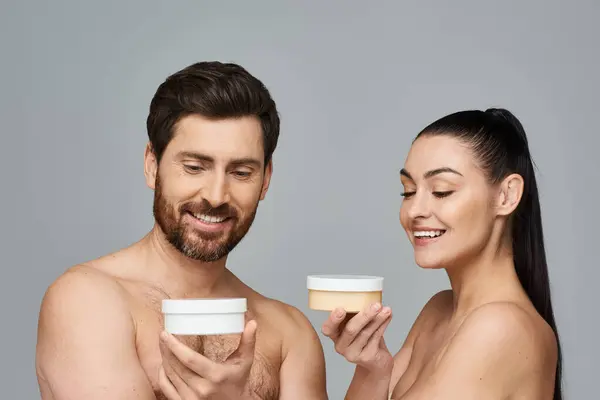 Un couple séduisant tient élégamment un pot de crème, mettant en valeur leur routine de soins de la peau. — Photo de stock