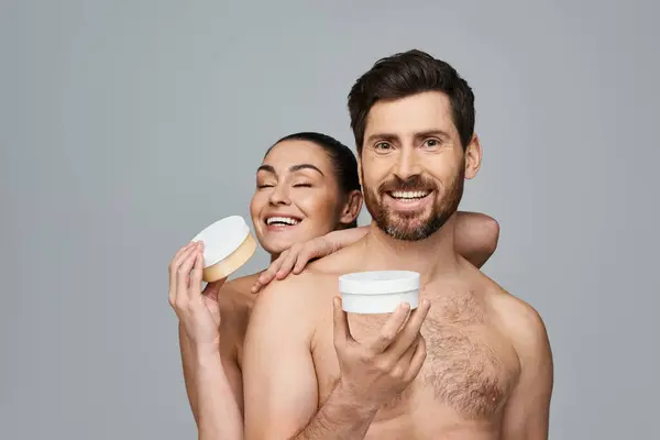 Alluring couple elegantly hold a jar of cream, showcasing their skincare routine. — Stock Photo