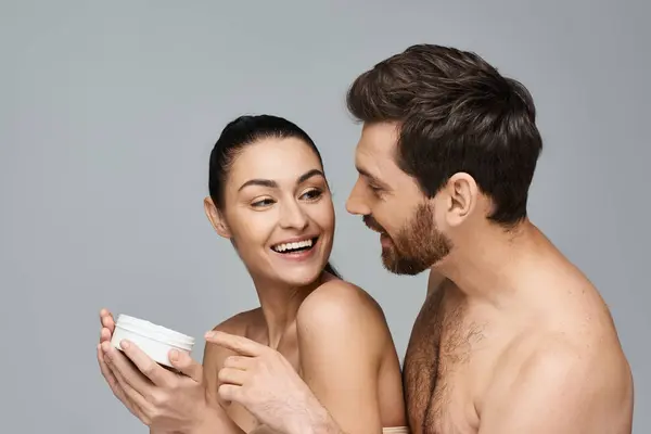 Un uomo e una donna, sorridenti, che tengono la crema in un ritratto. — Foto stock