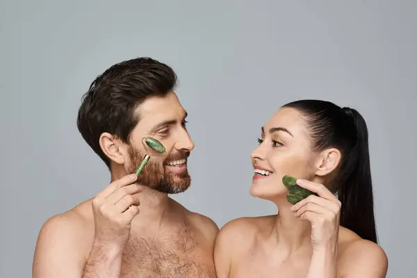 Um casal, irradiando beleza, usando rolo de rosto e gua sha juntos. — Fotografia de Stock