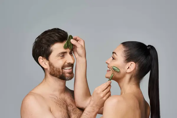 Appealing couple, radiating beauty, using face roller and gua sha together. — Stock Photo