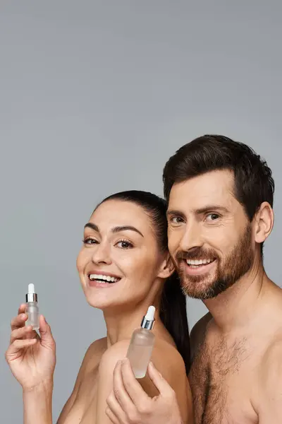 Appealing man and woman using serum as skin care. — Stock Photo