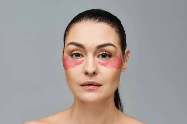 A woman with pink eye patches enhancing her face. — Stock Photo