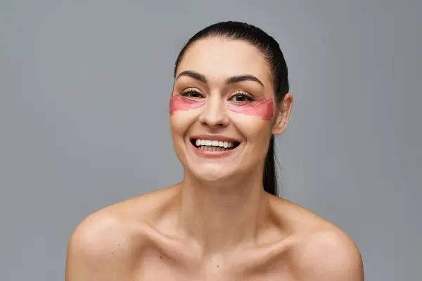 Веселая женщина с розовыми повязками на глазах, усиливающими ее лицо. — стоковое фото