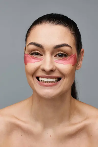 Fröhliche Frau mit rosa Augenklappen, die ihr Gesicht verschönern. — Stockfoto