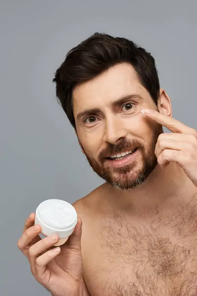 Un hombre en forma sostiene un frasco de crema. - foto de stock