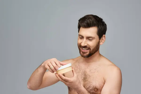 Bearded man holds a jar of cream. — Stock Photo
