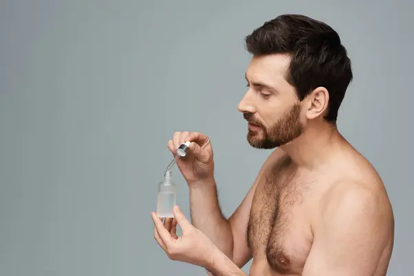 Un hombre sin camisa sostiene una botella de suero. - foto de stock