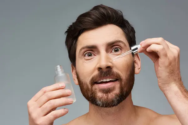 Привабливий чоловік наносить сироватку на обличчя. — Stock Photo